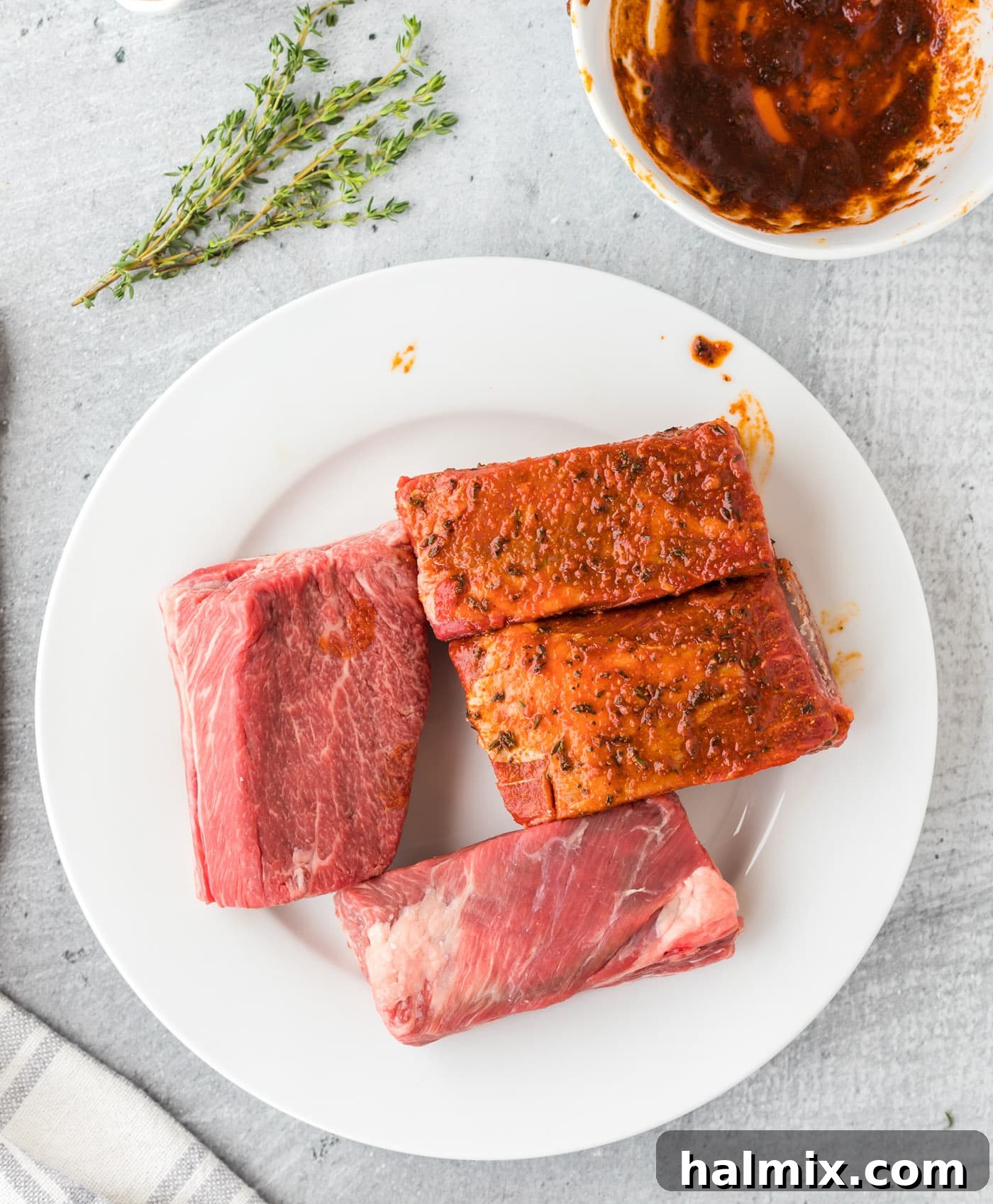 Hands rubbing seasoning into beef short ribs