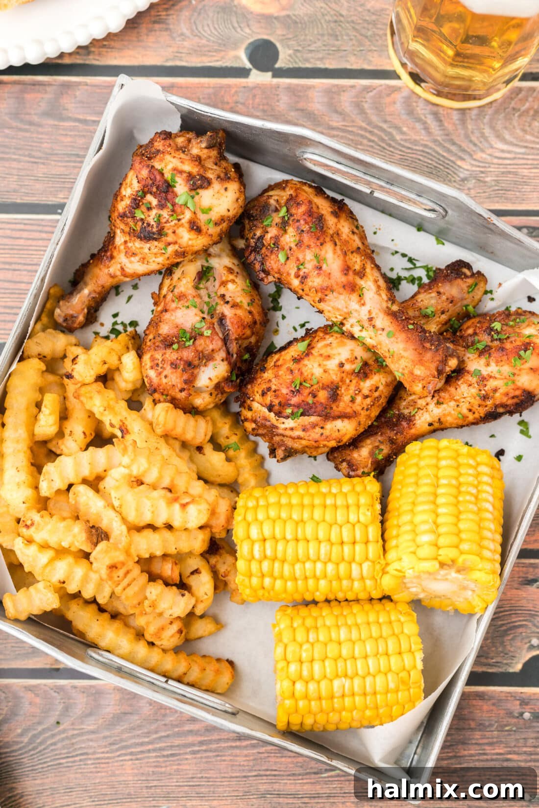 Golden Brown Baked Drumsticks 3 Baked Chicken Legs served with fries and corn on a plate