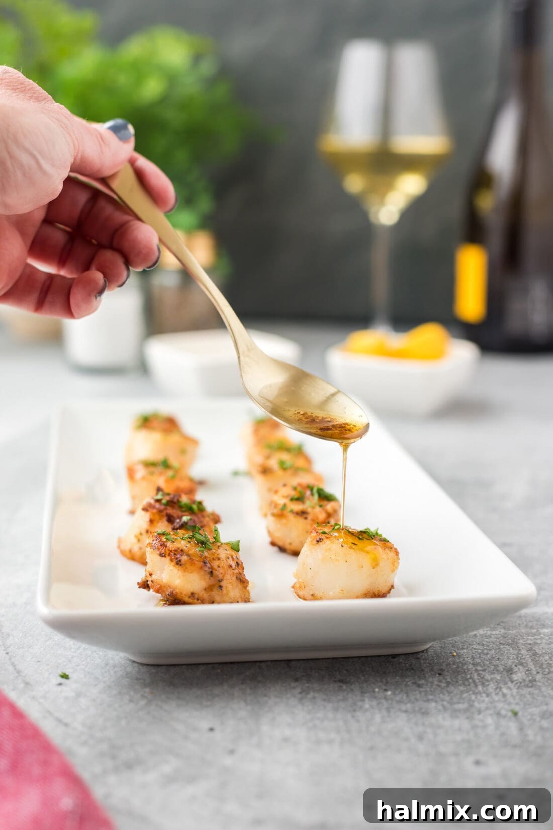 Close-up of golden brown pan-seared scallops being drizzled with butter in a skillet