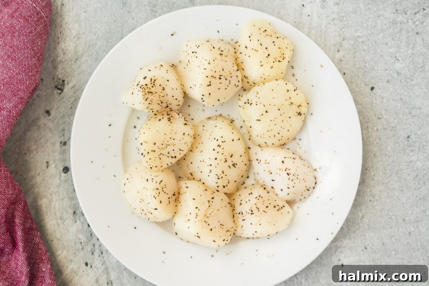 Cleaned scallops seasoned with salt and pepper on a plate