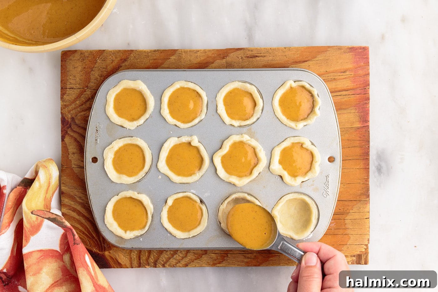 Petite Pumpkin Delights 14 adding pumpkin pie filling to pie dough in muffin pan