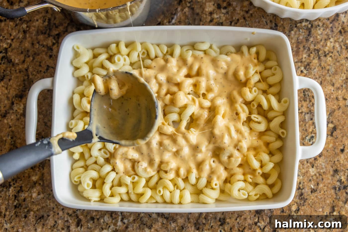 pasta being layered into a baking dish for lobster mac and cheese