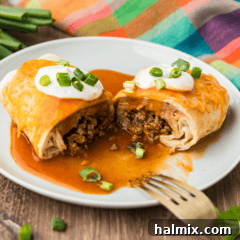 A close up photo of a Taco Bell enchirito copycat cut in half resting on a plate, showing the layers of filling.