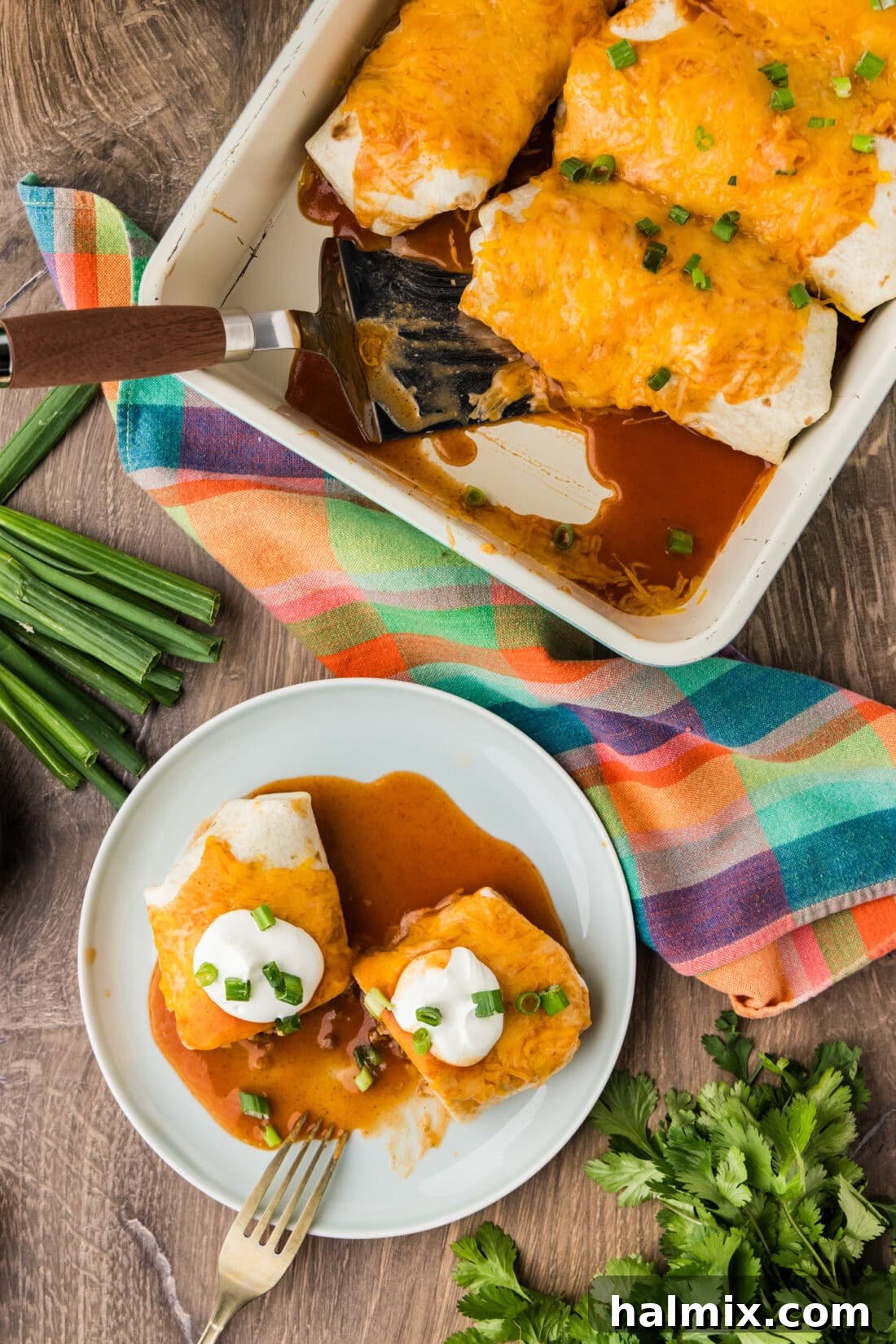Two homemade Taco Bell Enchirito copycats, one cut in half, on a plate with a baking pan in the background.