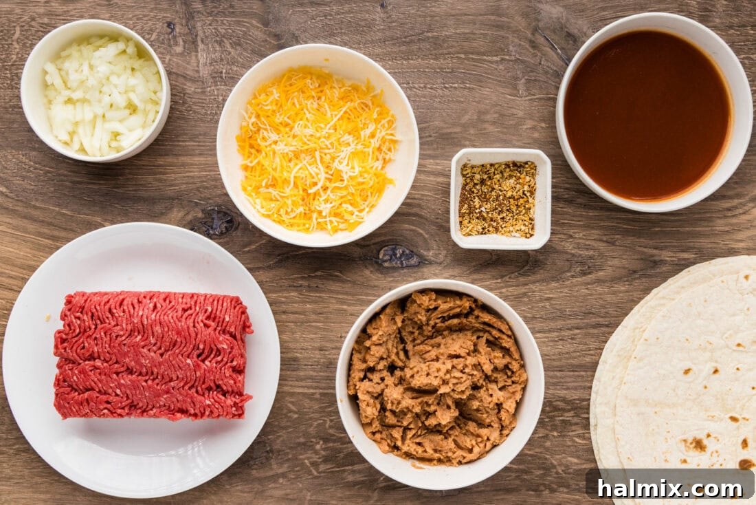 A flat lay photo of all ingredients required to make homemade enchiritos, including ground beef, tortillas, cheese, and sauce.