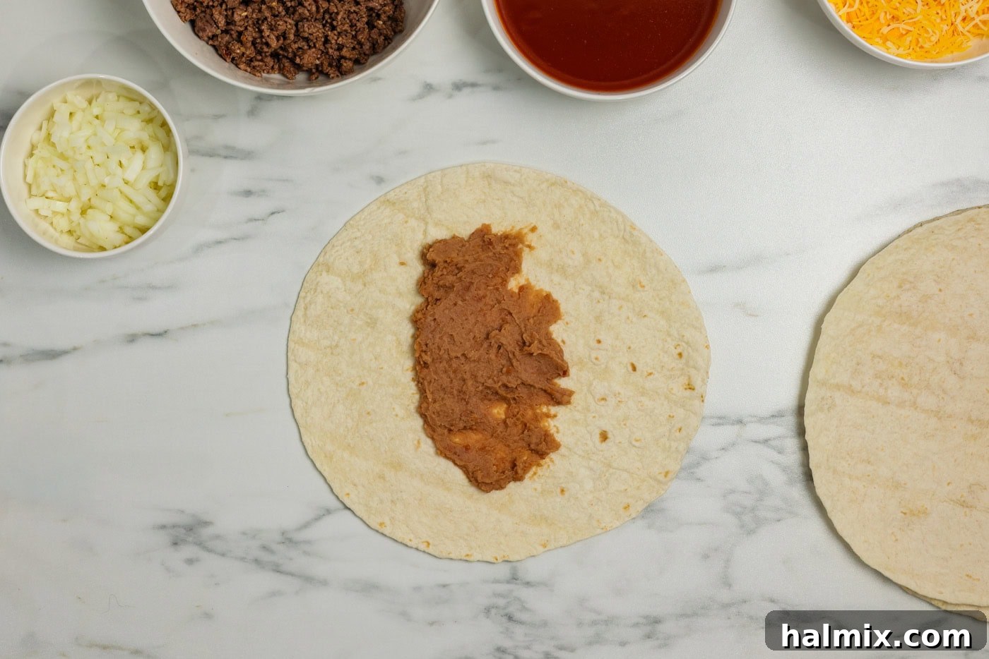Refried beans spread on a flour tortilla.