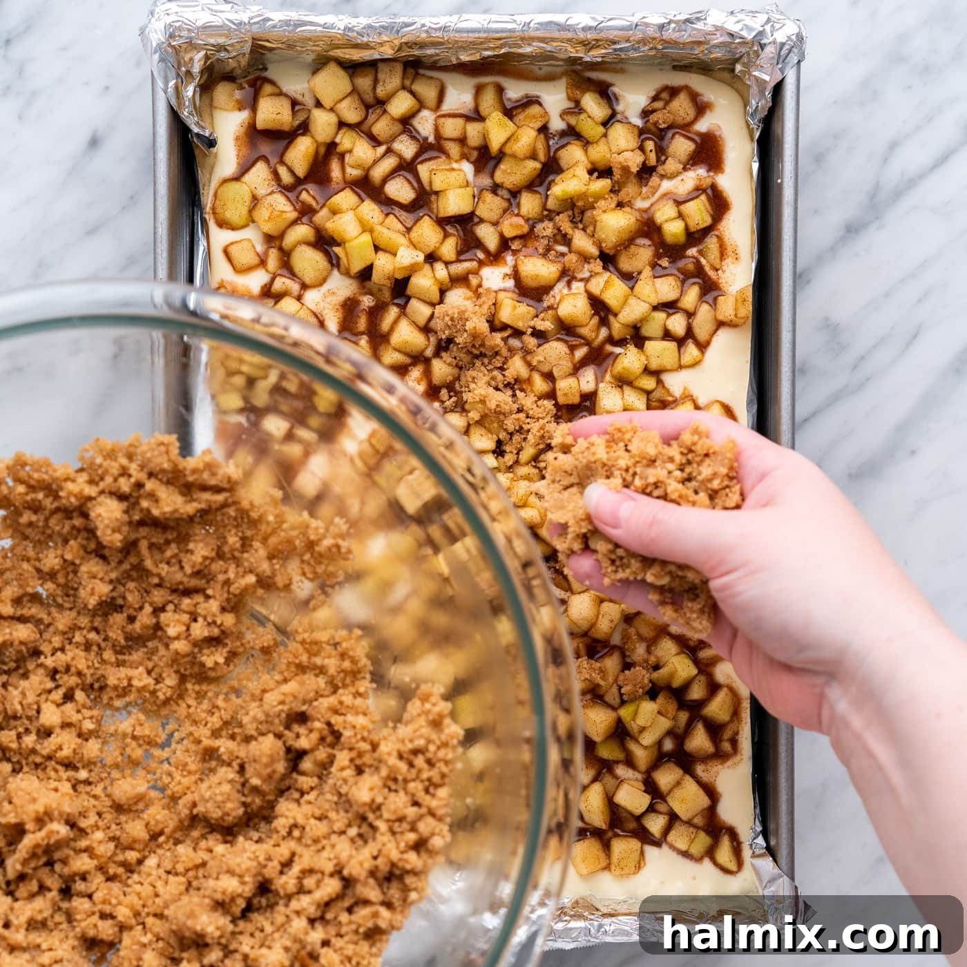 Spiced Apple Caramel Cheesecake Bars 18 sprinkling streusel topping on top of caramel apple cheesecake bars