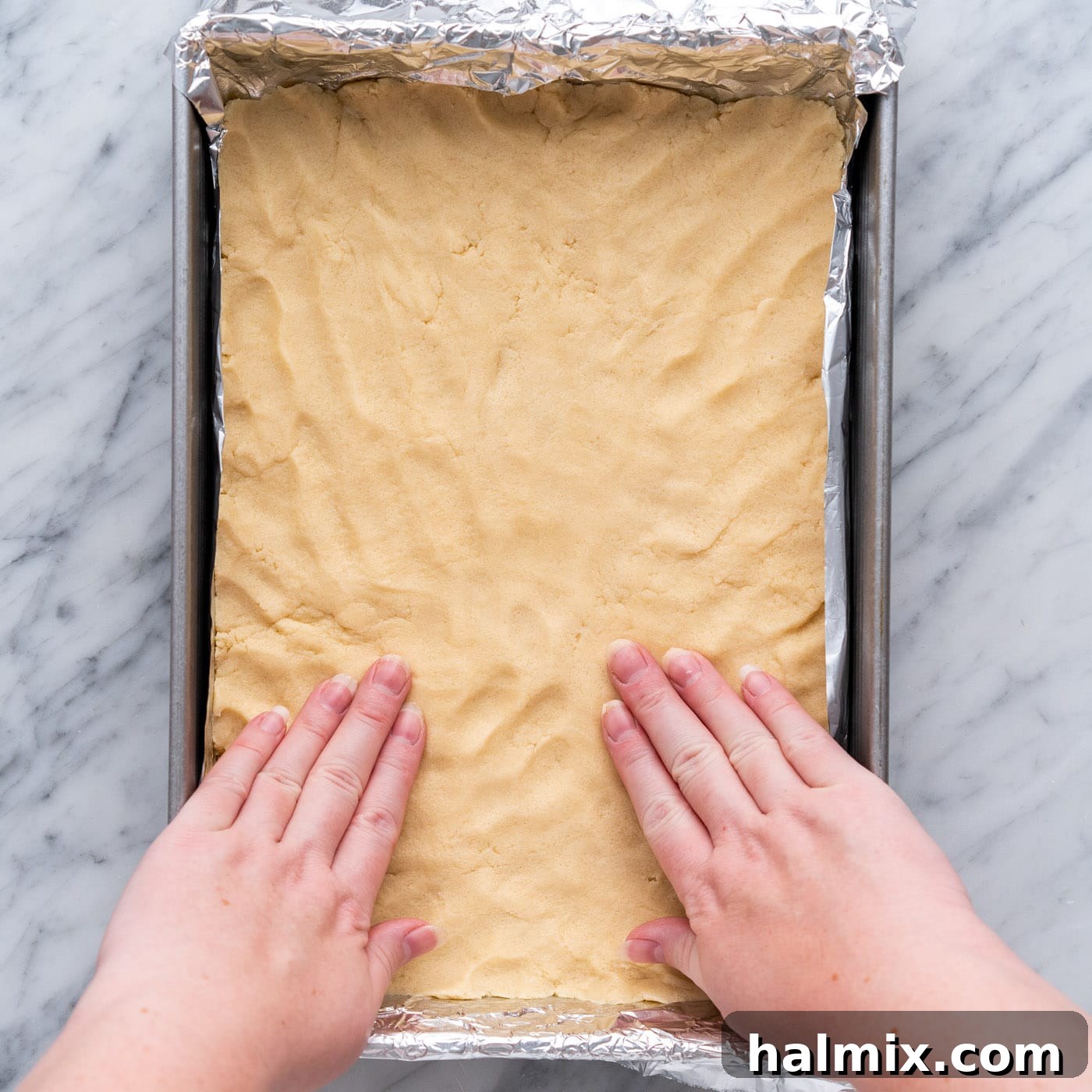 Spiced Apple Caramel Cheesecake Bars 10 hands flattening shortbread crust in a baking pan