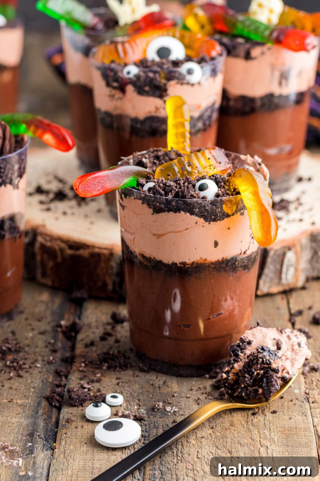 Close-up of a single Halloween Dirt Cup, adorned with colorful gummy worms, showcasing its delicious layers.