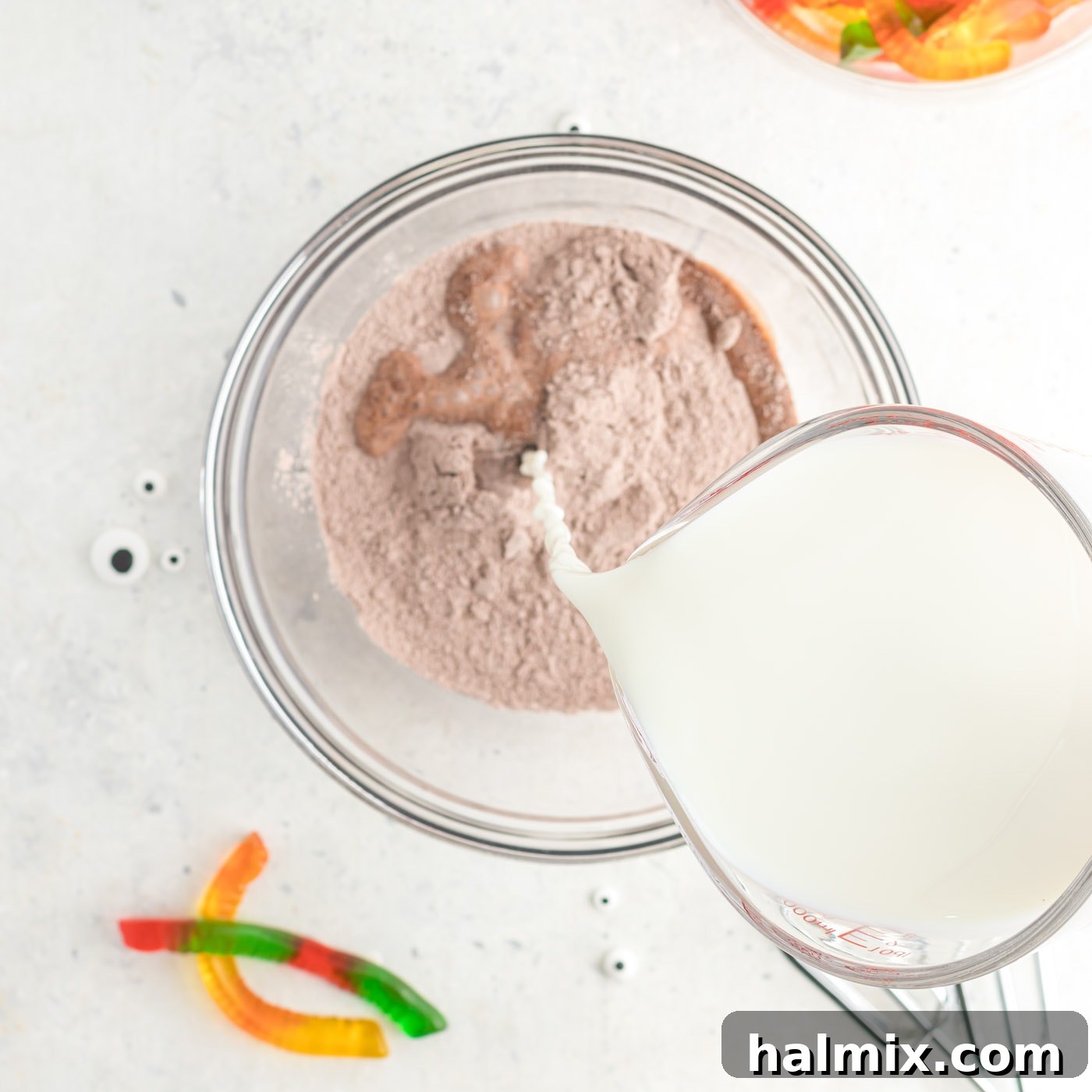 Pouring milk into a bowl containing instant chocolate pudding mix, beginning the pudding preparation process.