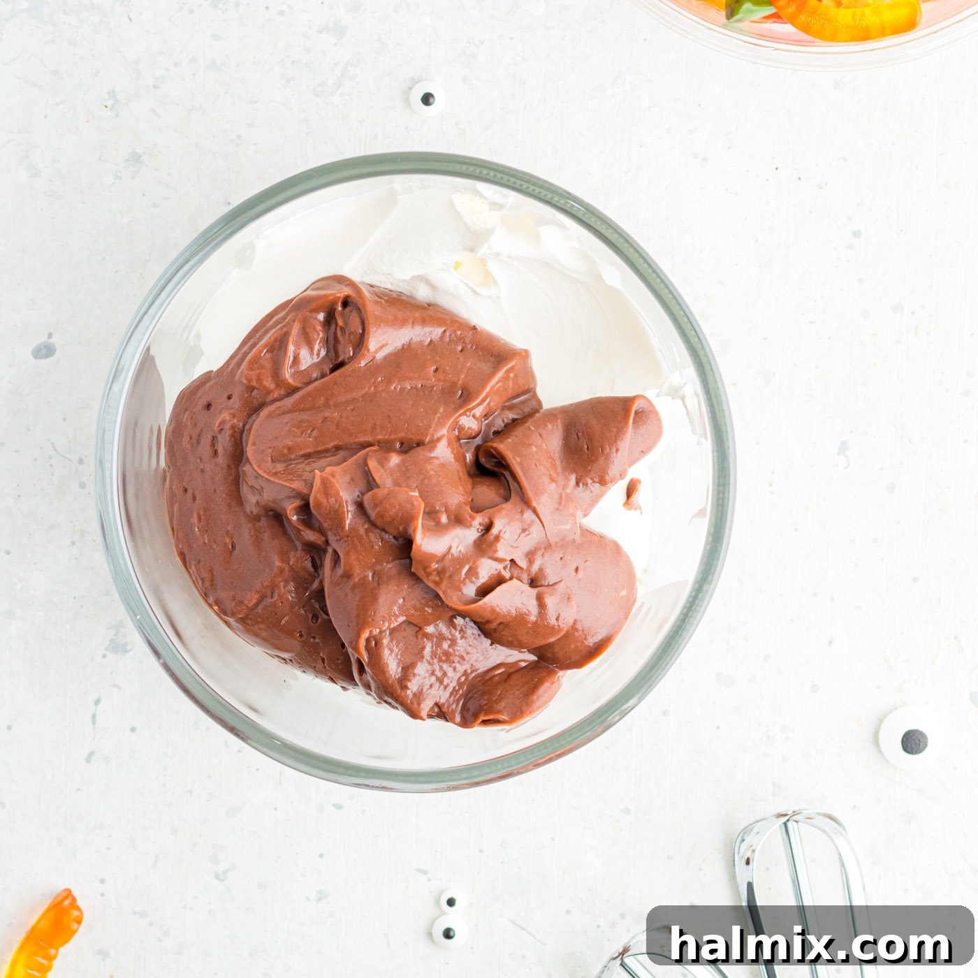 A medium bowl containing both Cool Whip and a portion of the prepared chocolate pudding, ready to be mixed for a lighter layer.