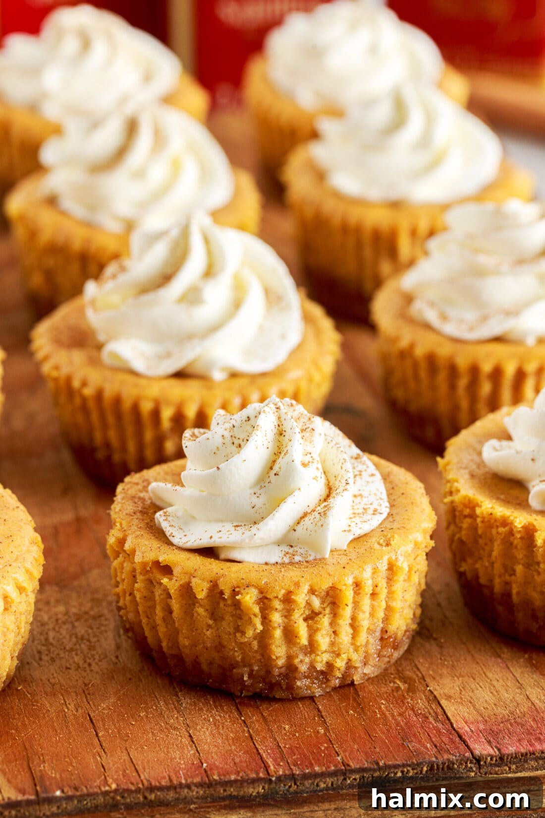 Spiced Pumpkin Cheesecake Minis 2 Delightful Mini Pumpkin Cheesecakes arranged on a rustic cutting board, ready for a fall gathering.