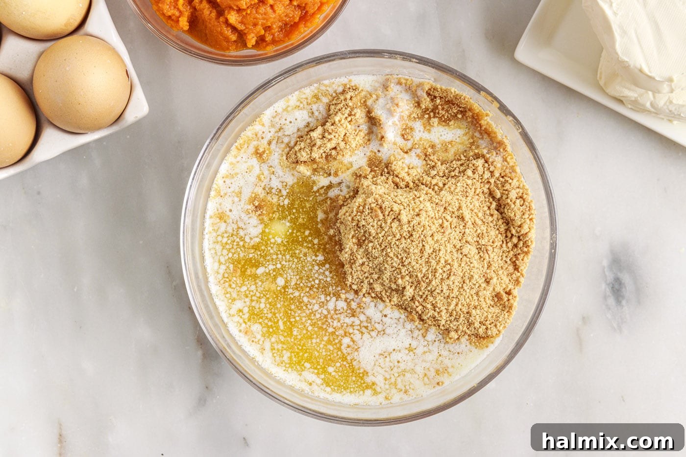Spiced Pumpkin Cheesecake Minis 5 A bowl containing graham cracker crumbs, melted butter, and sugar, mixed together.