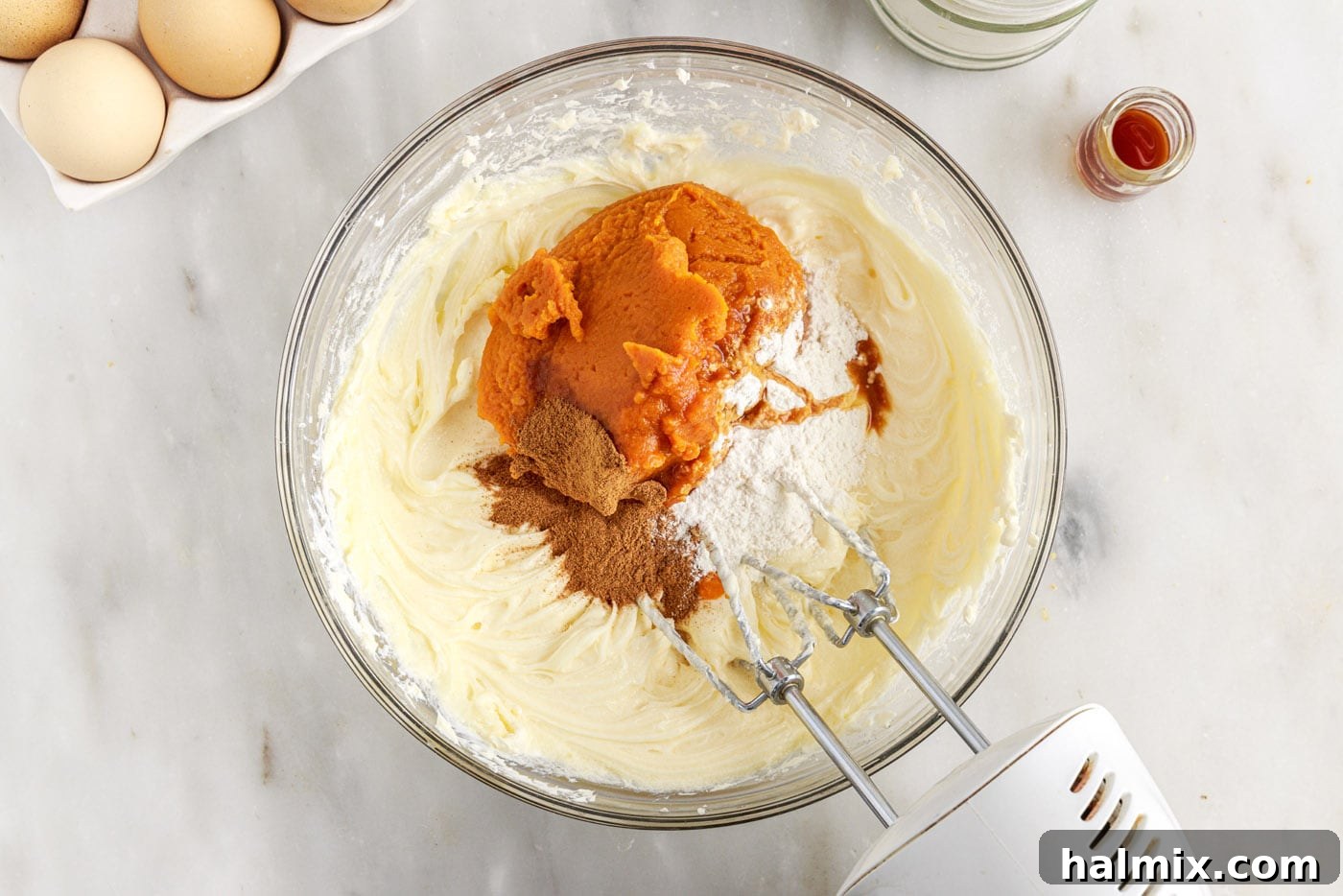 Spiced Pumpkin Cheesecake Minis 9 Pumpkin cheesecake filling being mixed in a bowl with an electric mixer, showing its smooth consistency.