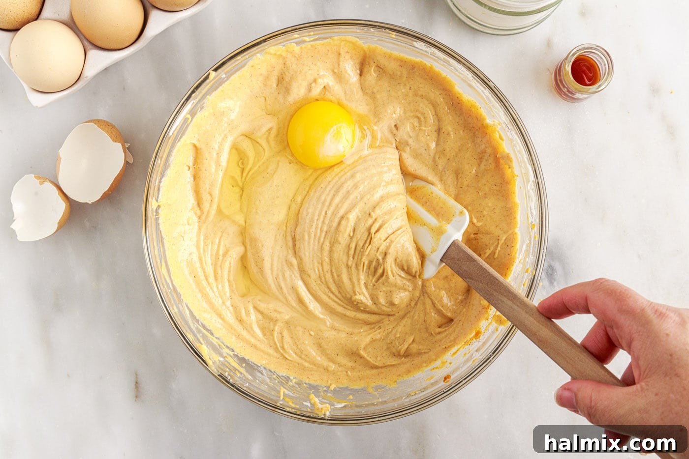 Spiced Pumpkin Cheesecake Minis 10 Eggs being gently mixed into the pumpkin cheesecake filling in a bowl.