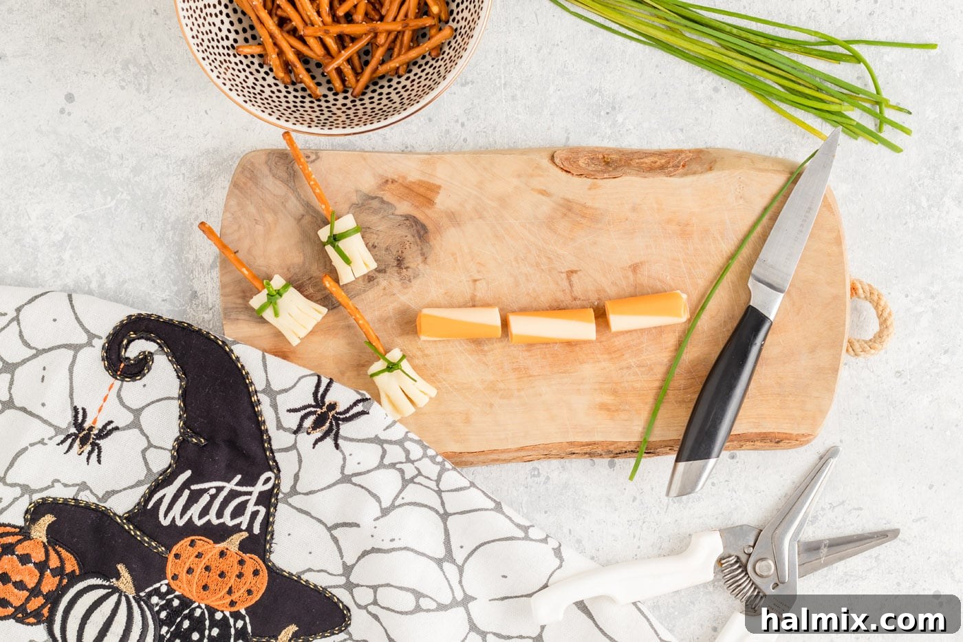 Cheesy Pretzel Broomsticks 5 String cheese sticks neatly cut into three equal sections on a cutting board, ready for the next step.