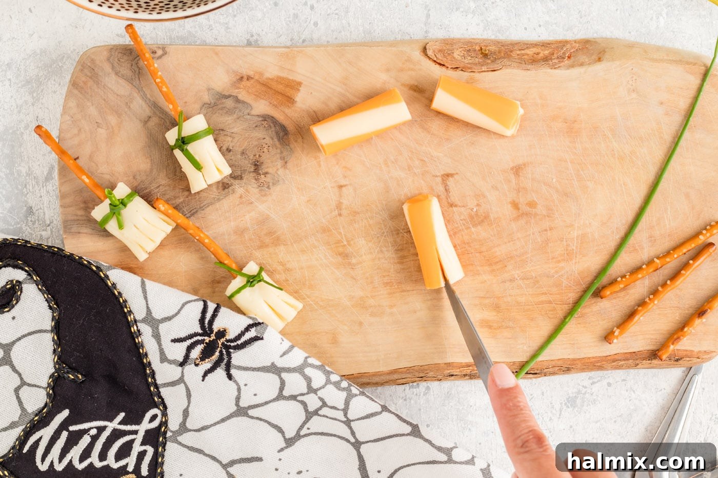 Cheesy Pretzel Broomsticks 6 A knife slicing vertical lines into a string cheese section to create the broom-like bristles.