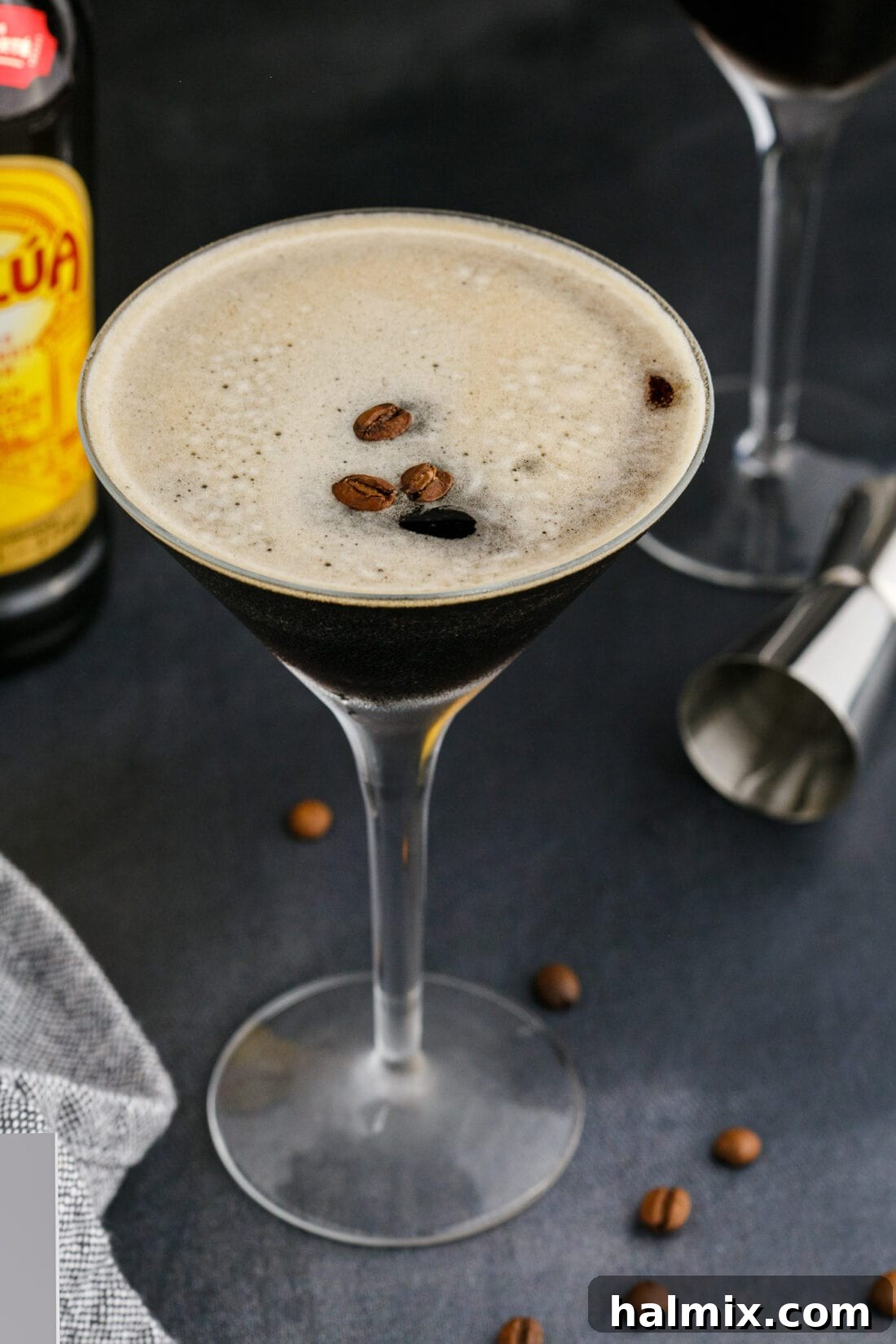 Espresso Martini garnished with whole coffee beans, showcasing its dark liquid and thick frothy top in a martini glass.