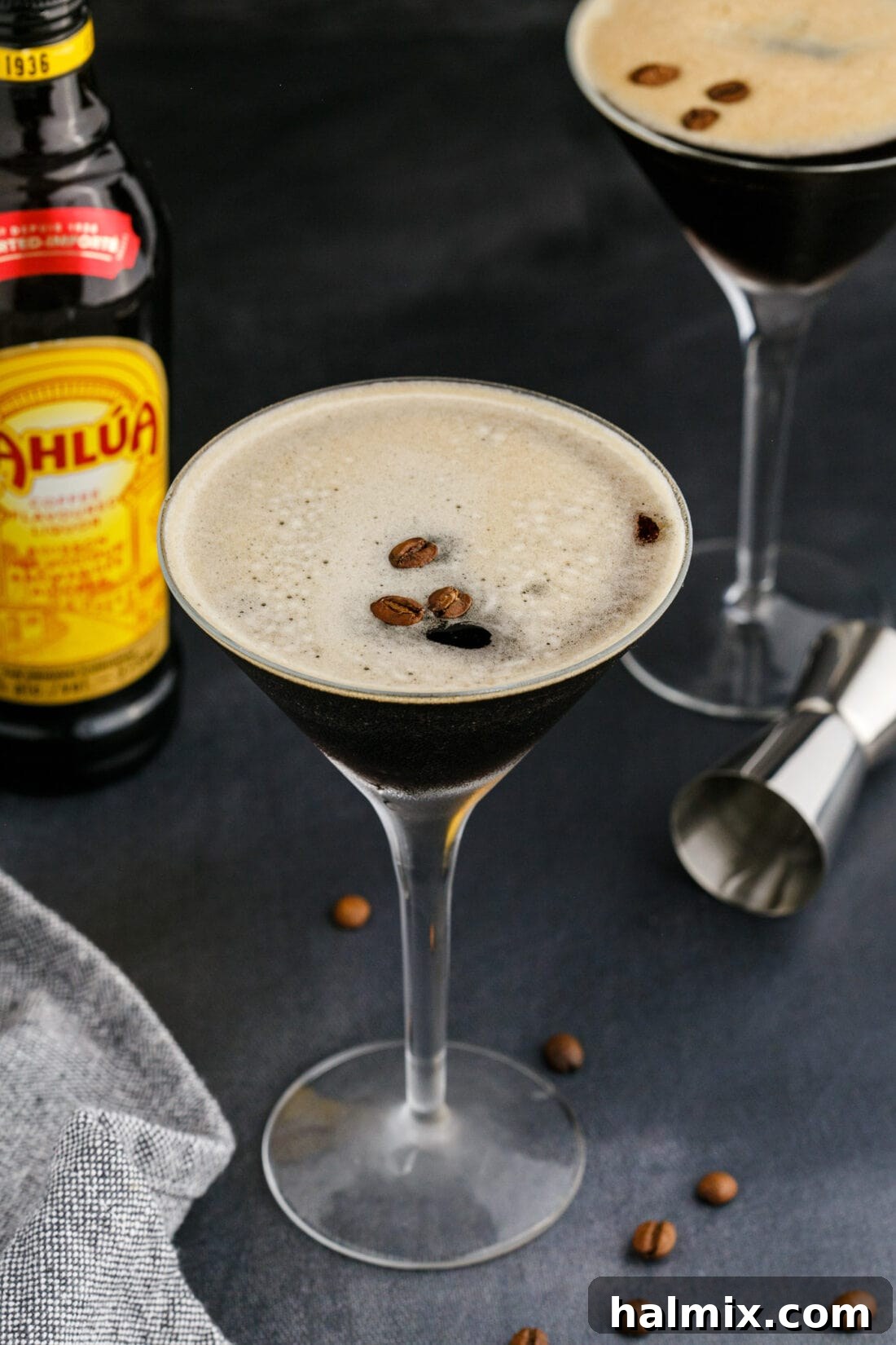 An Espresso Martini in a martini glass with a blurred Kahlua bottle in the background, hinting at key ingredients.