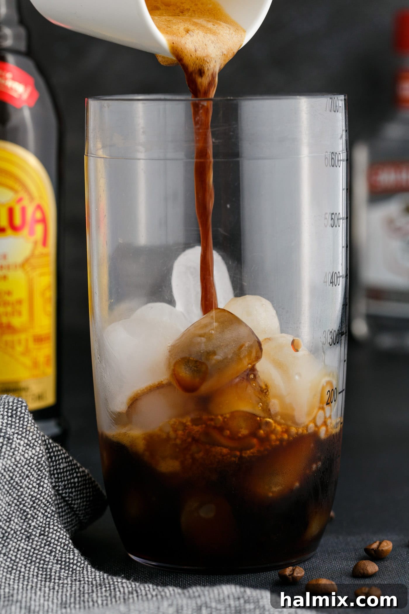 Pouring freshly brewed, chilled espresso into a cocktail shaker with ice.