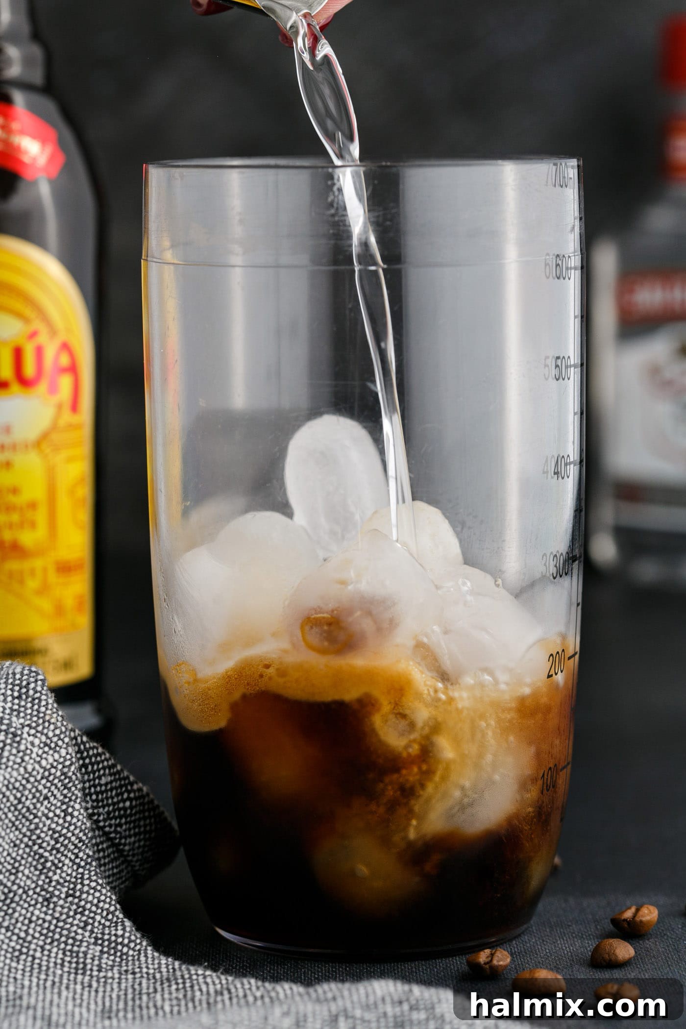 Adding vodka to the cocktail shaker, completing the liquid ingredients for the Espresso Martini.