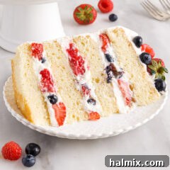 A slice of Chantilly Cake on a plate, garnished with fresh berries.