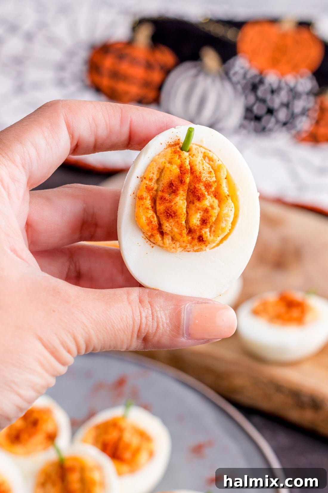 Spiced Pumpkin Deviled Bites 10 A hand holding a single pumpkin deviled egg, showcasing its detail