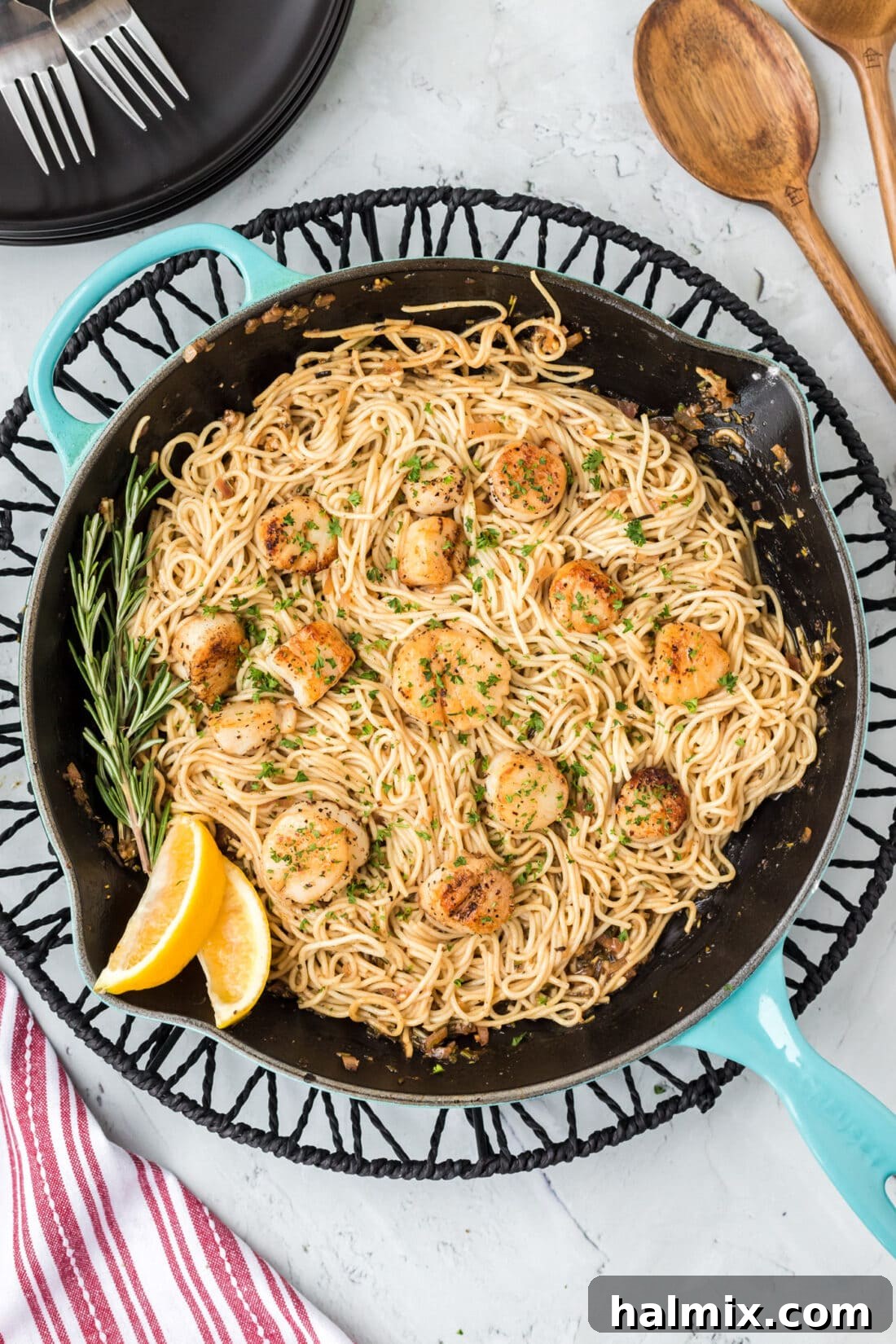 Close-up of a skillet filled with golden-crusted Scallop Pasta, garnished with fresh herbs