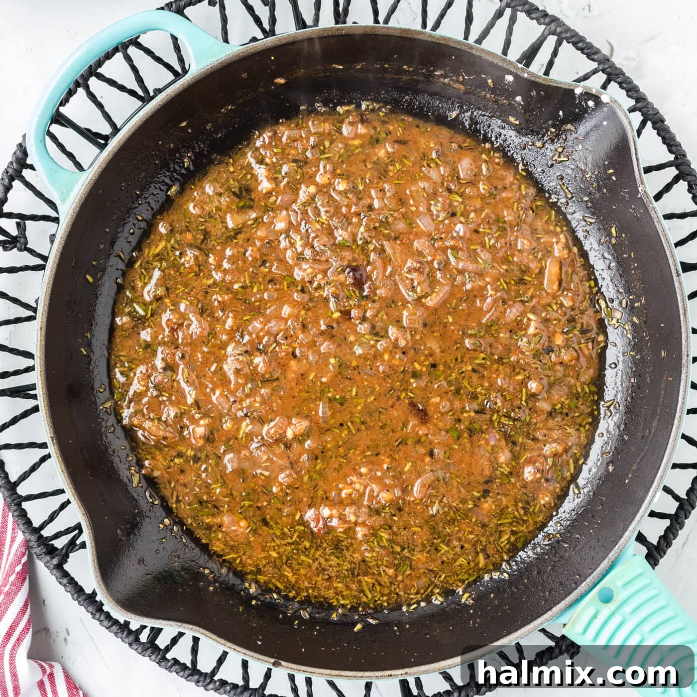Close-up of the white wine sauce simmering in a pan, with visible herbs and shallots