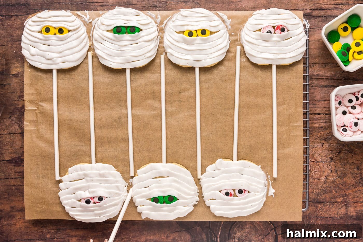Finished mummy cookie pops on a baking sheet, ready to set