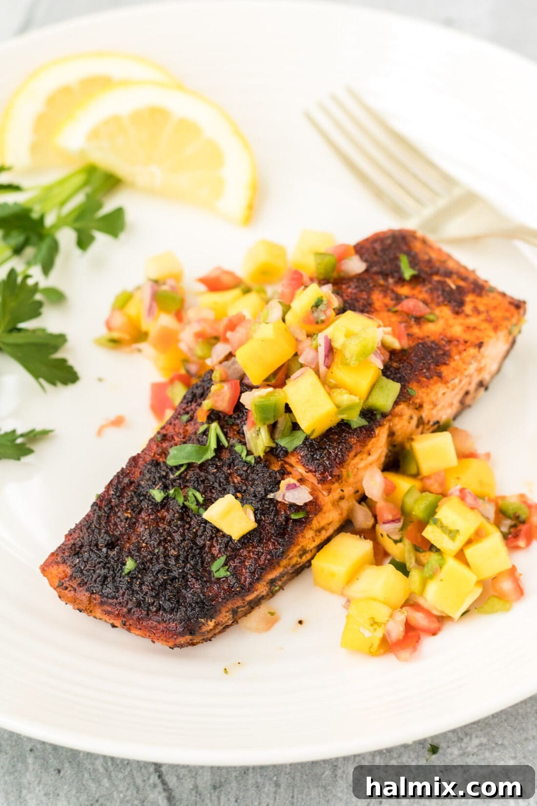 Cajun Seared Salmon 2 Blackened Salmon with vibrant mango salsa, showcasing a perfect crust and tender flakes.