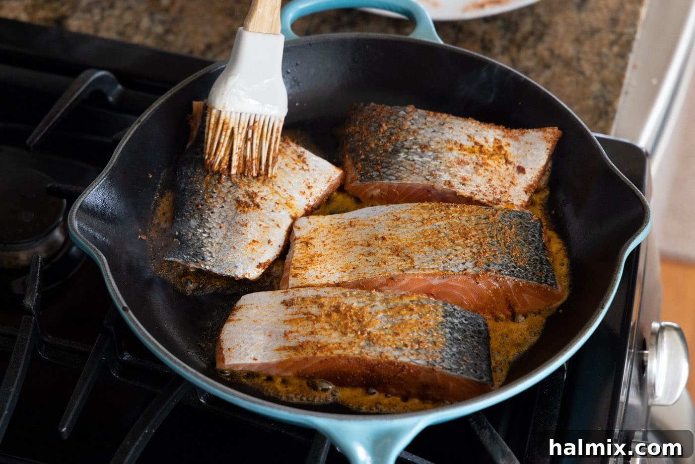 Cajun Seared Salmon 5 Brushing the skin side of salmon fillets with butter and seasoning while cooking in a skillet.