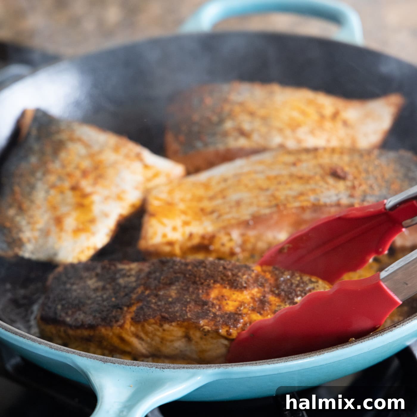 Cajun Seared Salmon 6 Blackened salmon fillets, perfectly seared with a dark crust, resting in a skillet after cooking.