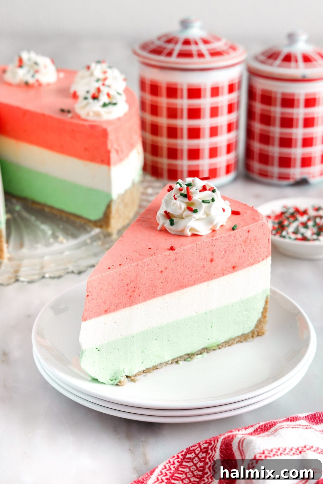 Rainbow Ripple Gelatin Pie 2 Slice of a vibrant, multi-layered jello pie on a plate, showcasing its festive colors and creamy texture, ready to be enjoyed.