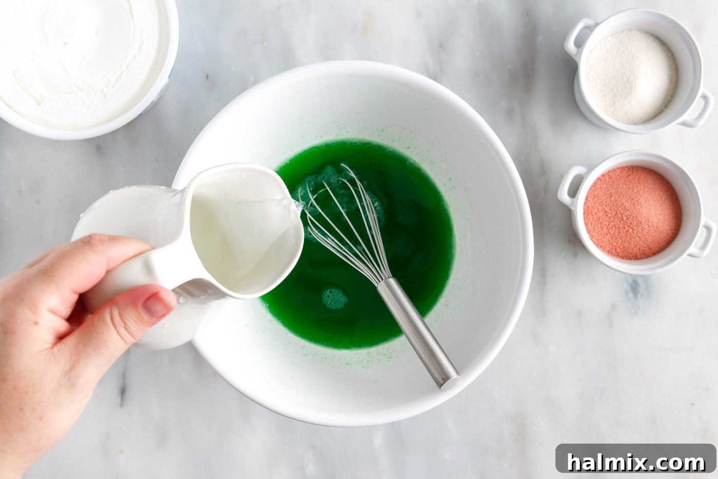 Mixing jello powder with boiling water in a bowl until fully dissolved for the first layer.