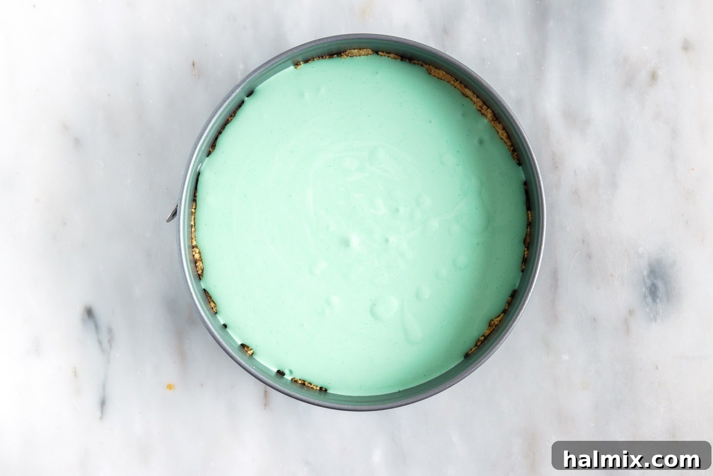 The first layer of whipped lime jello mixture evenly spread in the graham cracker crust in a springform pan.