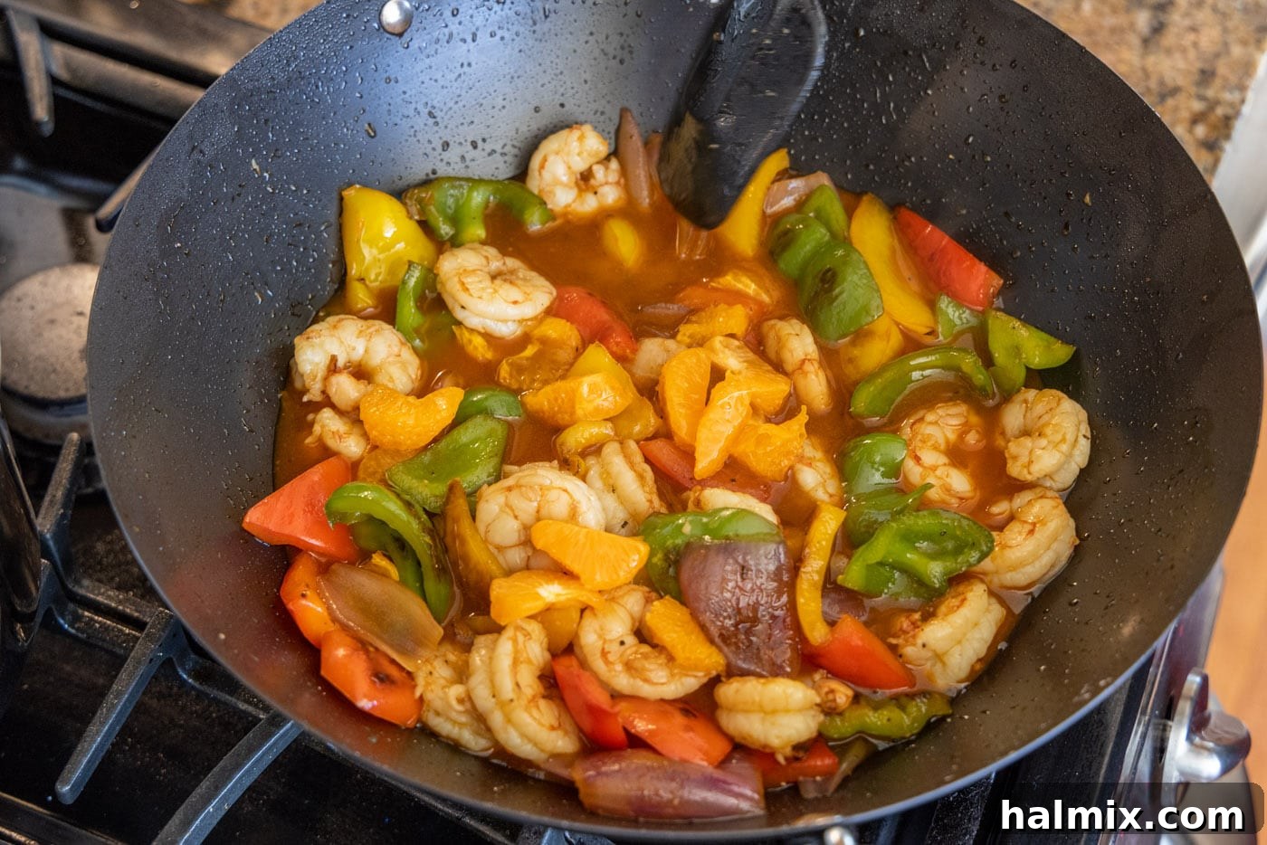 The finished Citrus Pepper Shrimp, tossed with its delectable sauce and fresh clementine wedges, glowing in a wok, ready to be dished out.