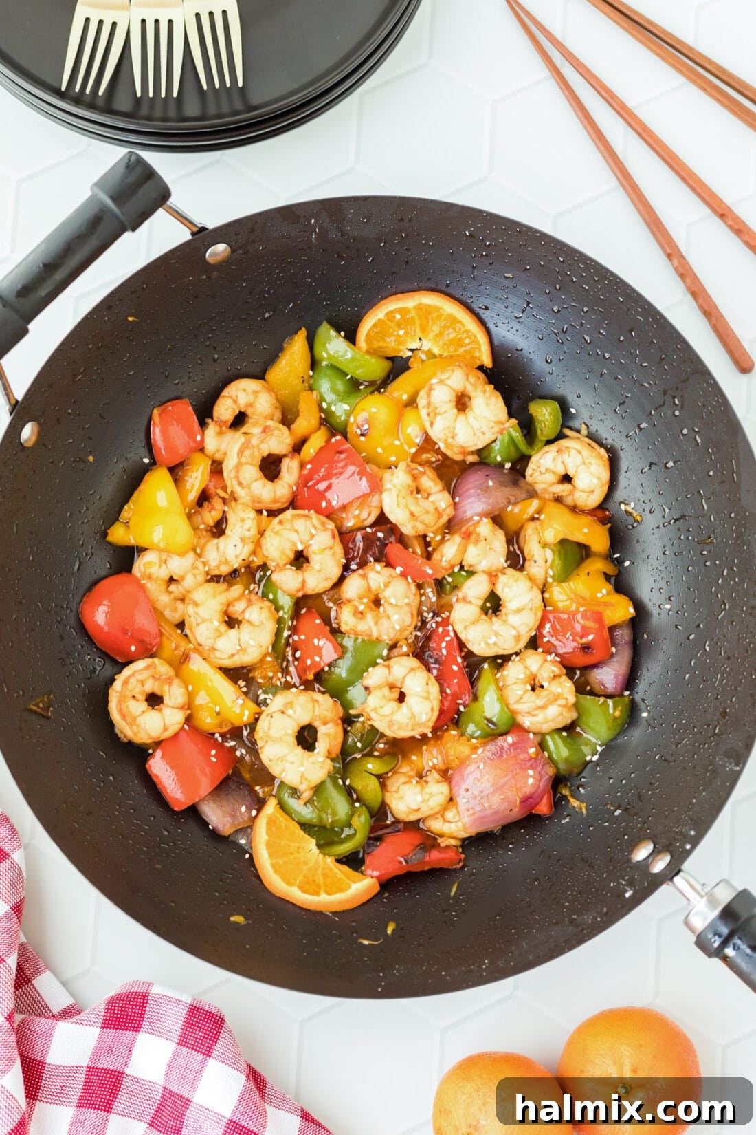 A large wok filled with freshly cooked Citrus Pepper Shrimp, featuring succulent shrimp, colorful bell peppers, and red onions glistening in a sweet and savory sauce.