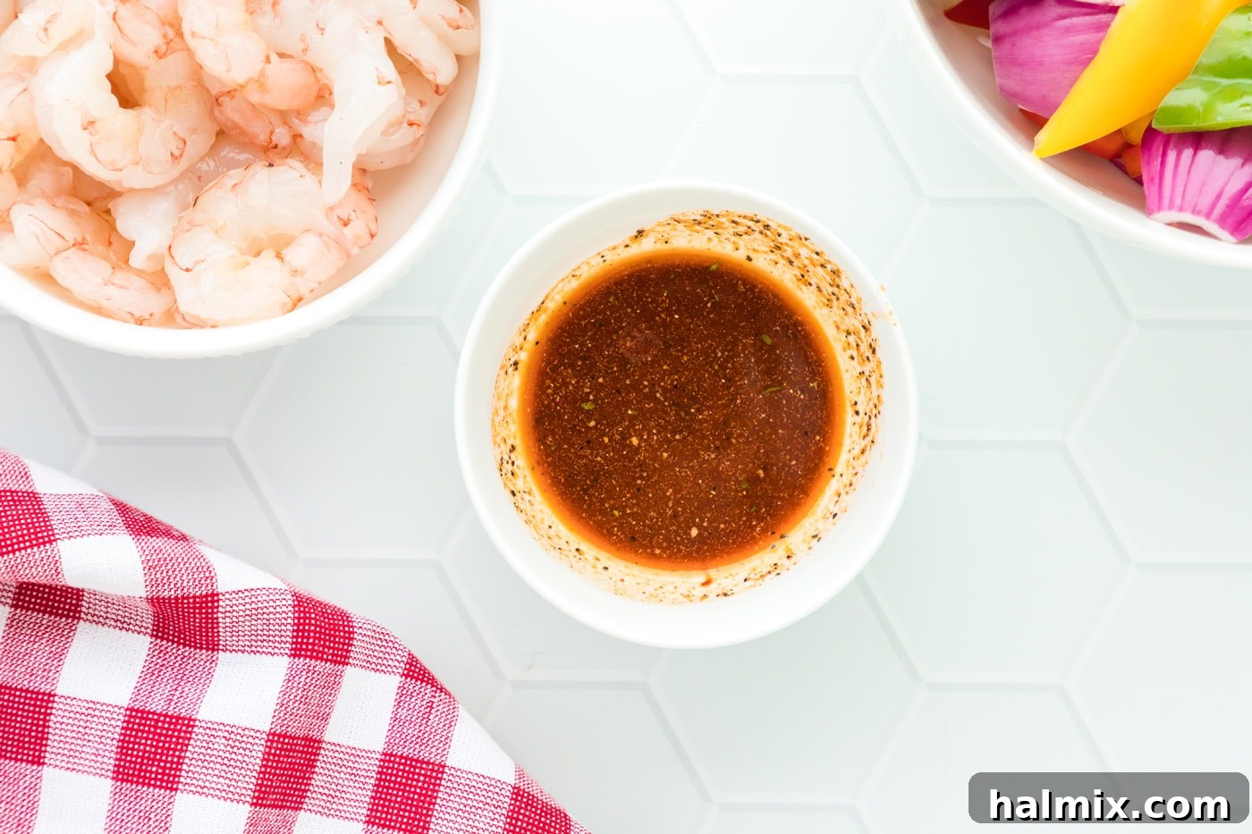A small bowl containing olive oil, cayenne pepper, black pepper, and garlic salt, ready to be mixed into a seasoning for shrimp.