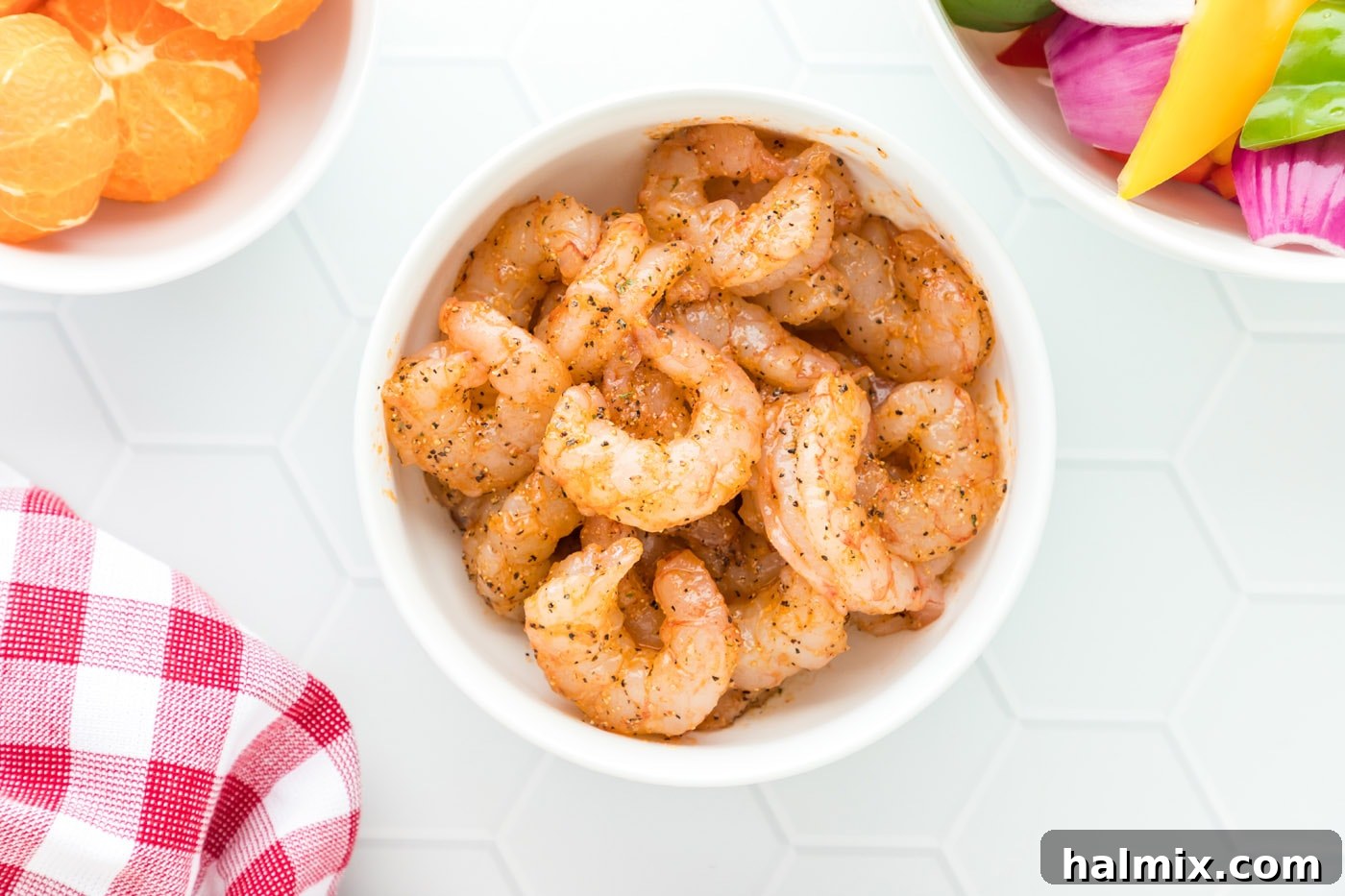 A bowl of raw shrimp, expertly coated with a vibrant seasoning mix, ensuring every piece is ready for cooking.