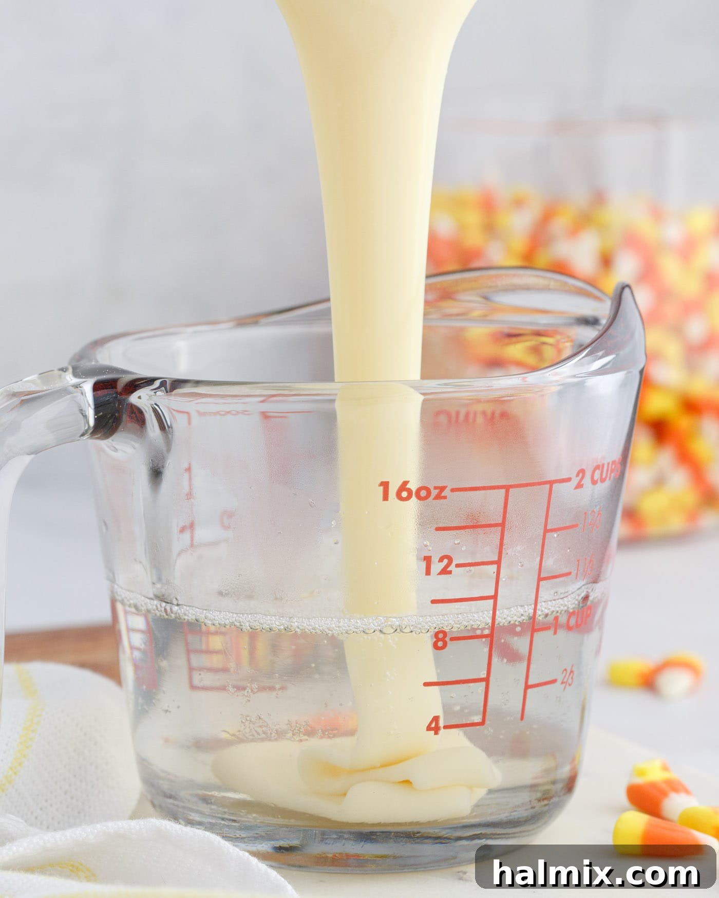 Mixing sweetened condensed milk into the unflavored gelatin and vodka mixture, forming the creamy white layer for the jello shots.