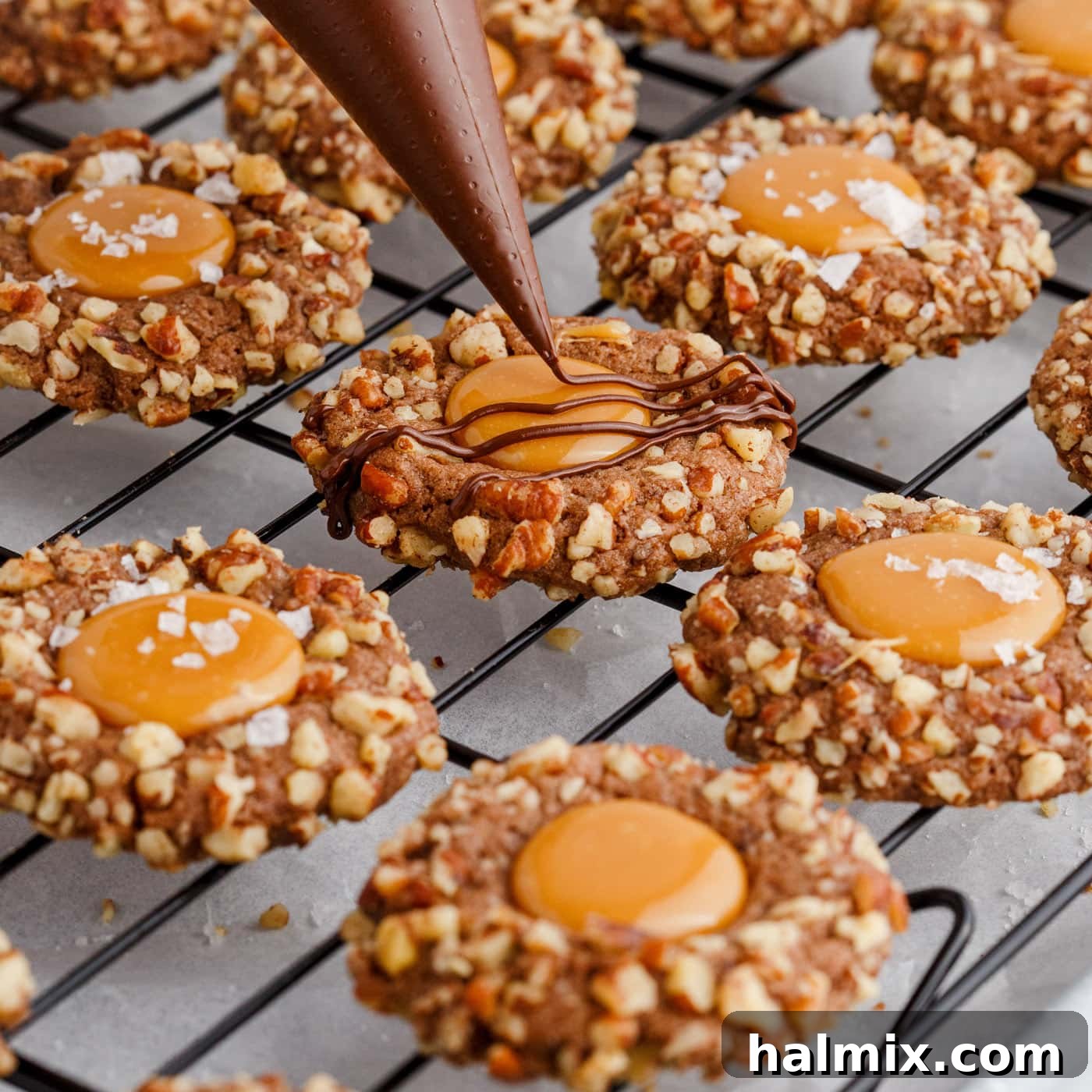 drizzling chocolate over turtle thumbprint cookies