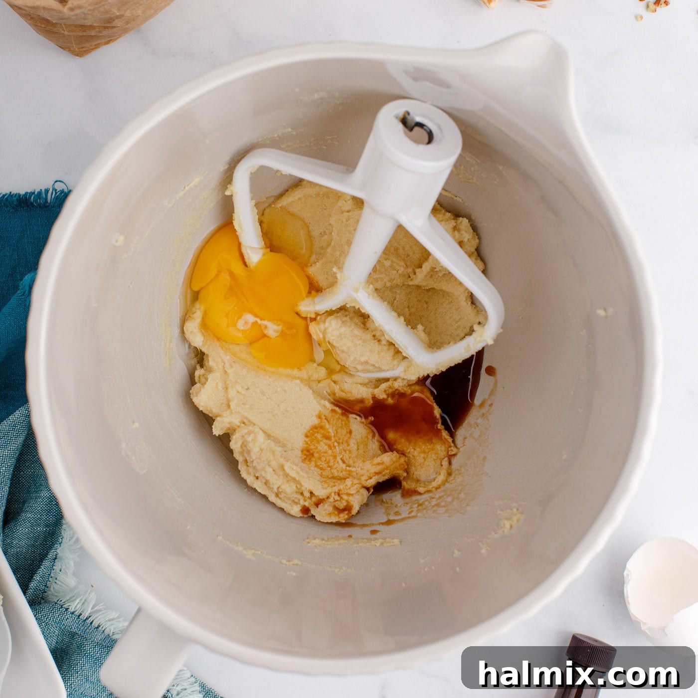 eggs and vanilla added to a mixer bowl with butter and sugars