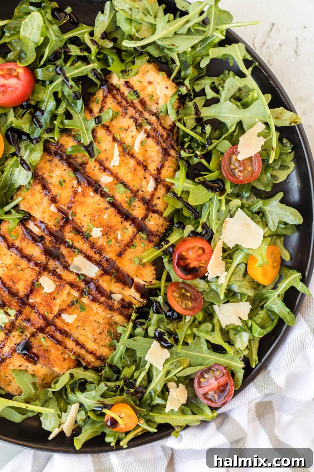 Crispy Golden Milanese Chicken 15 A vibrant plate of Chicken Milanese served alongside a fresh green salad with cherry tomatoes