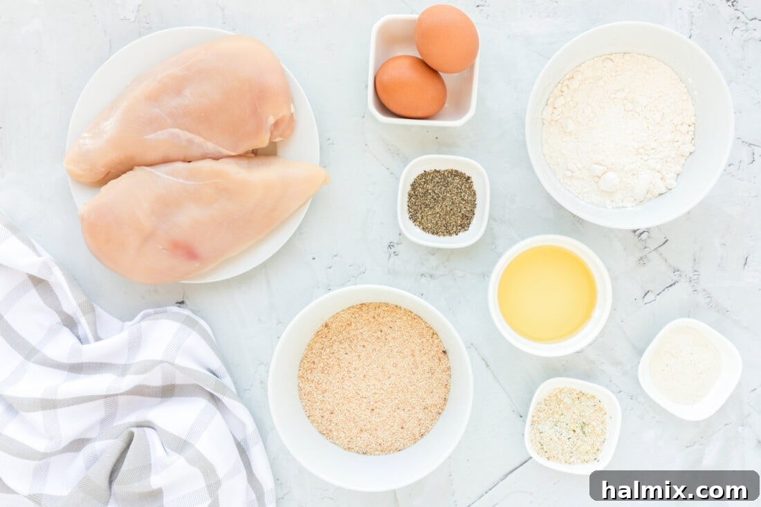 Crispy Golden Milanese Chicken 4 A selection of fresh ingredients laid out: chicken breasts, flour, breadcrumbs, eggs, and seasonings for Chicken Milanese