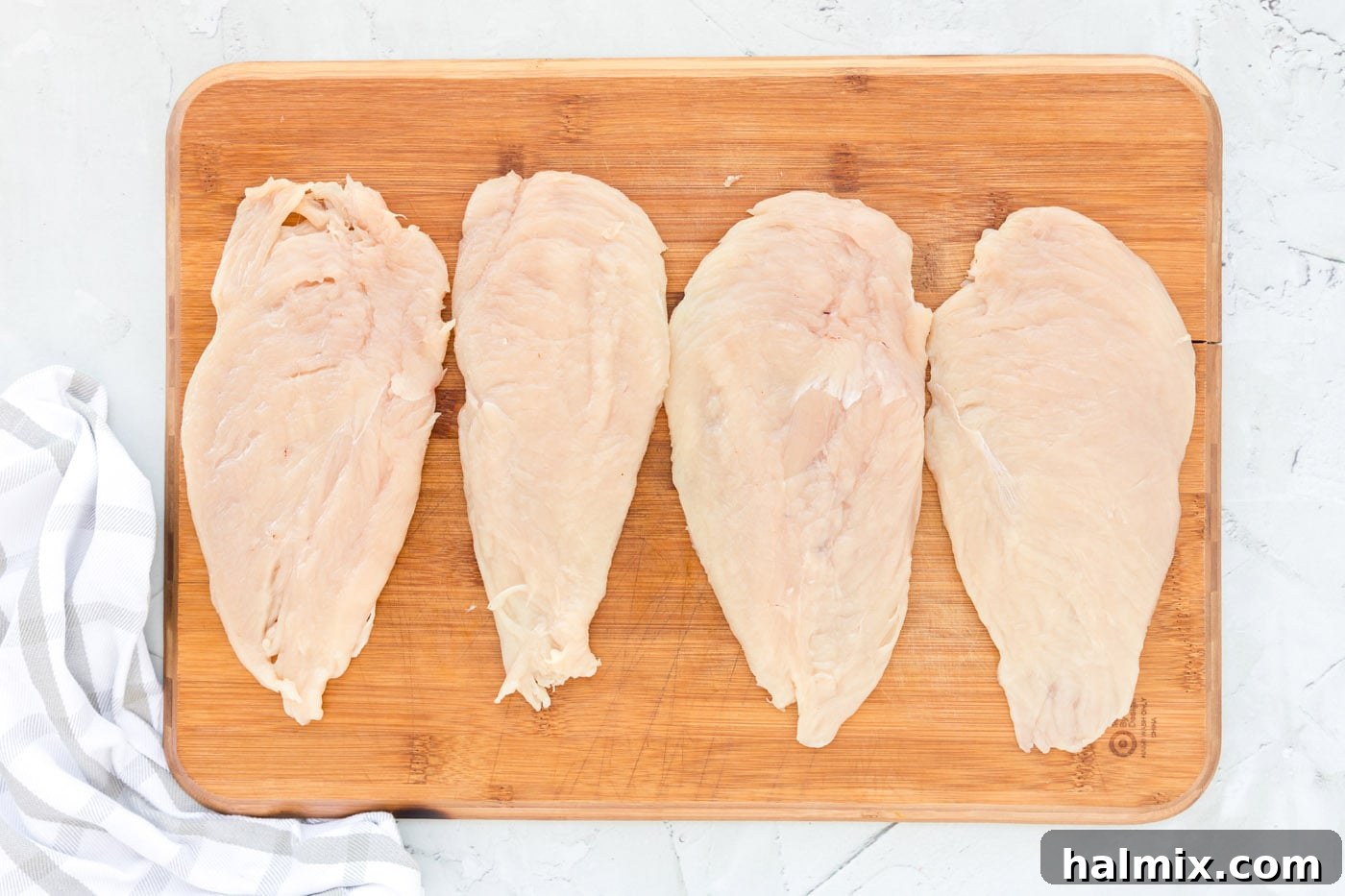 Thinly pounded chicken cutlets on a cutting board, ready for breading