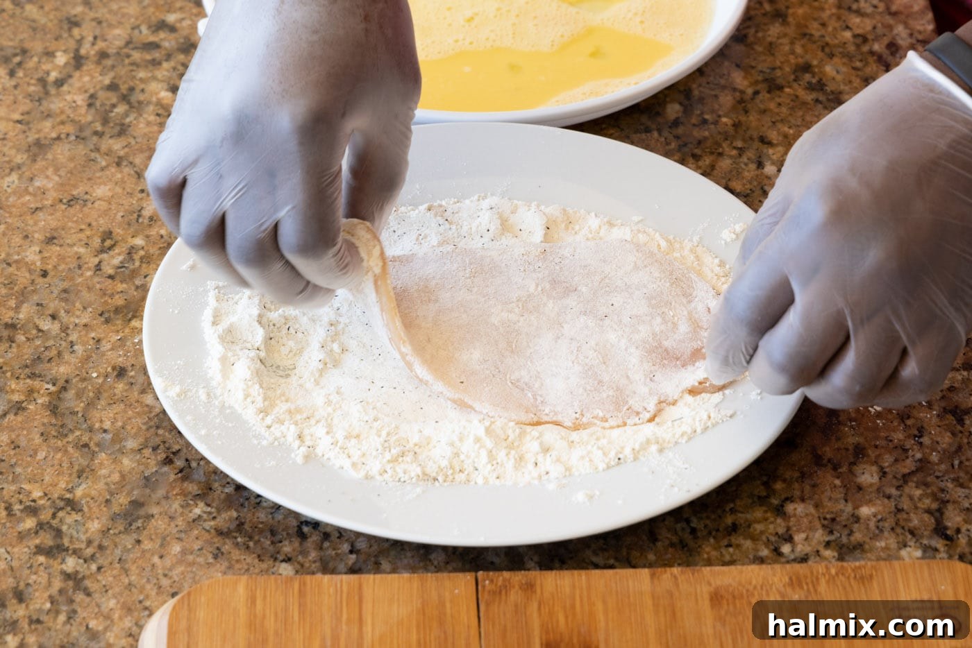 A chicken cutlet fully coated in flour, ready for the next step
