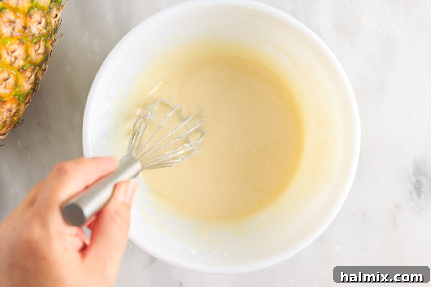 Luscious Pineapple Pound Cake 12 Ingredients for pineapple glaze being whisked together in a bowl until smooth and shiny.
