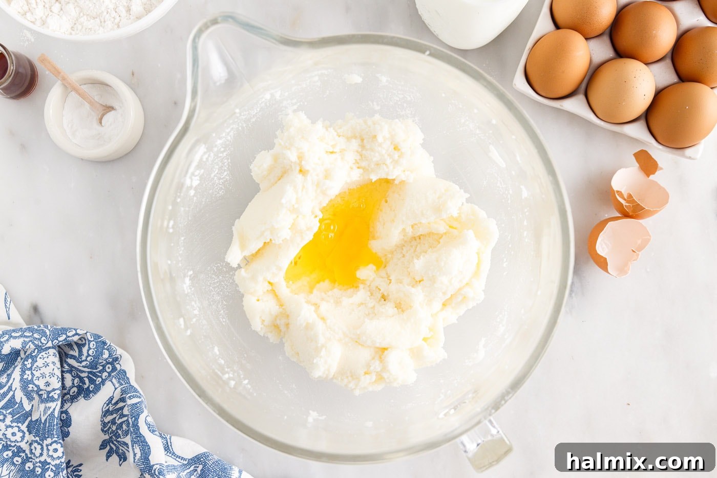 Luscious Pineapple Pound Cake 6 Eggs being added one by one to the creamed butter and sugar mixture in a mixing bowl, ensuring thorough incorporation for a fluffy cake.