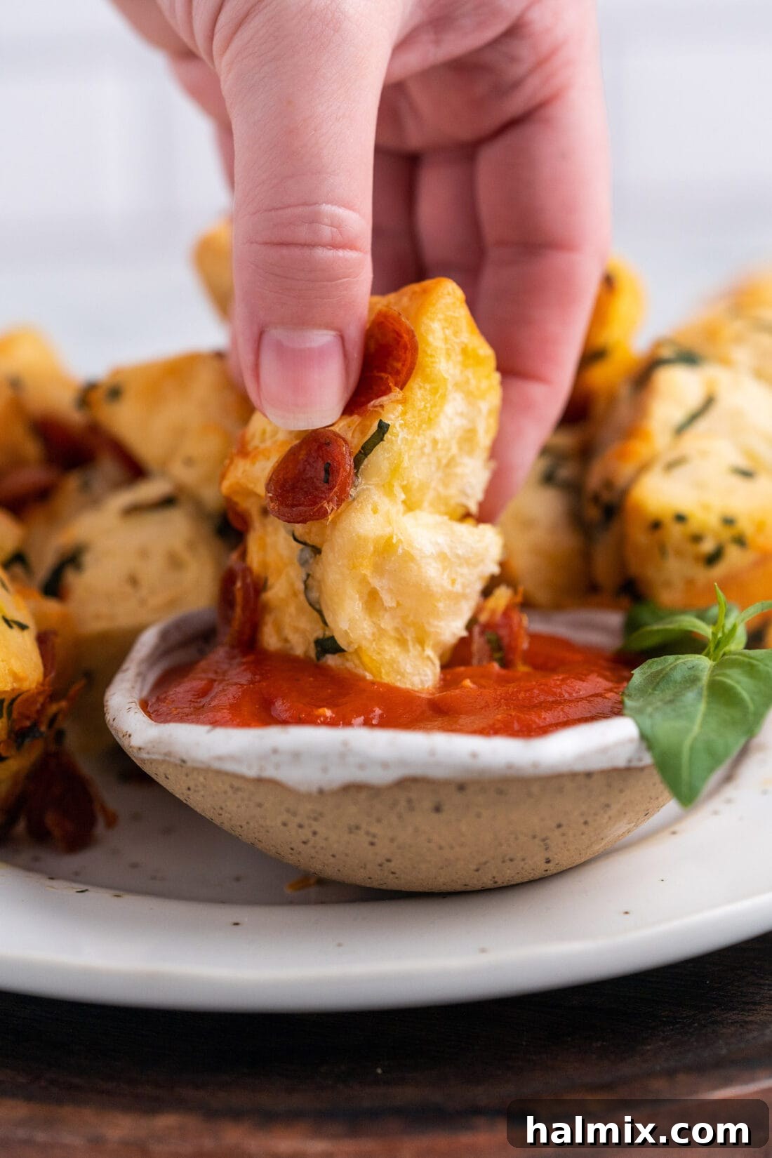 Pizza Zingers 2 Dipping a pizza bite in marinara sauce, showcasing its golden crust and cheesy interior.